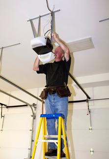 Expert Tech standing on a ladder fixing a mechanical garage door opener